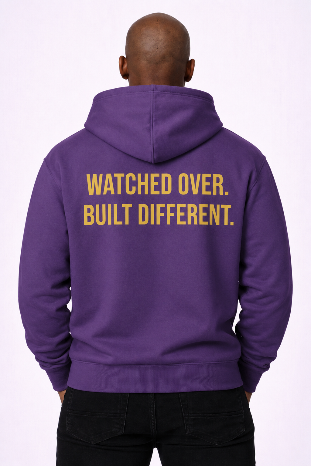 Watched Over. Built Different. — Back view model wearing purple hoodie with gold slogan